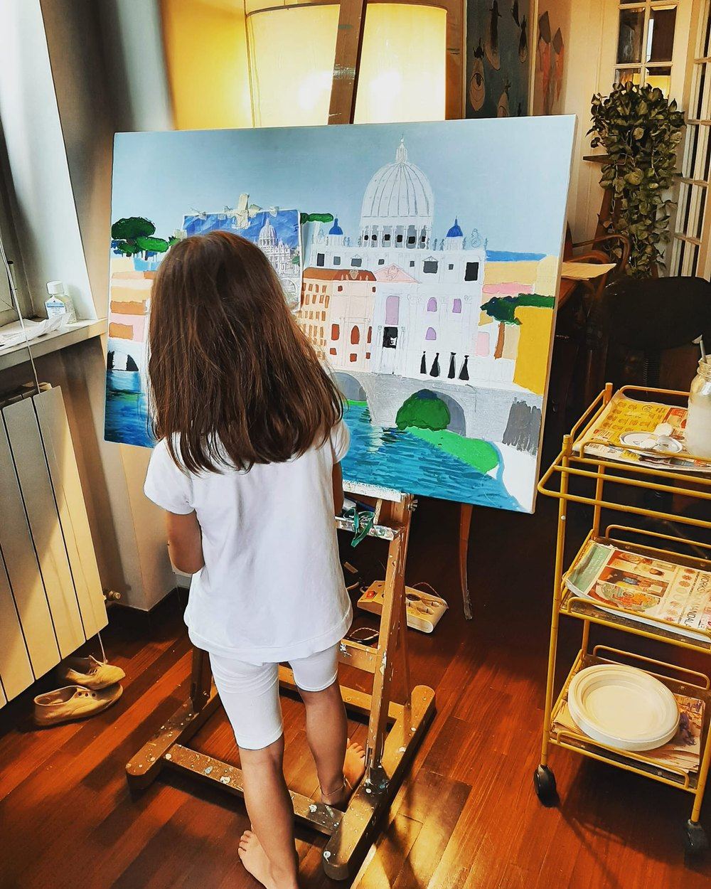 Bambina che dipinge una tela al cavalletto durante un corso di pittura a Roma